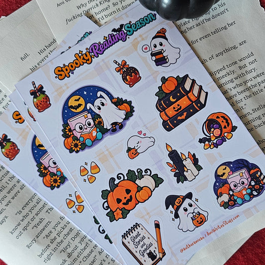 Halloween-themed sticker sheets featuring cute cartoon ghosts, pumpkins, candy corn, and a witch hat, displayed on top of open books with a small black pumpkin decoration.