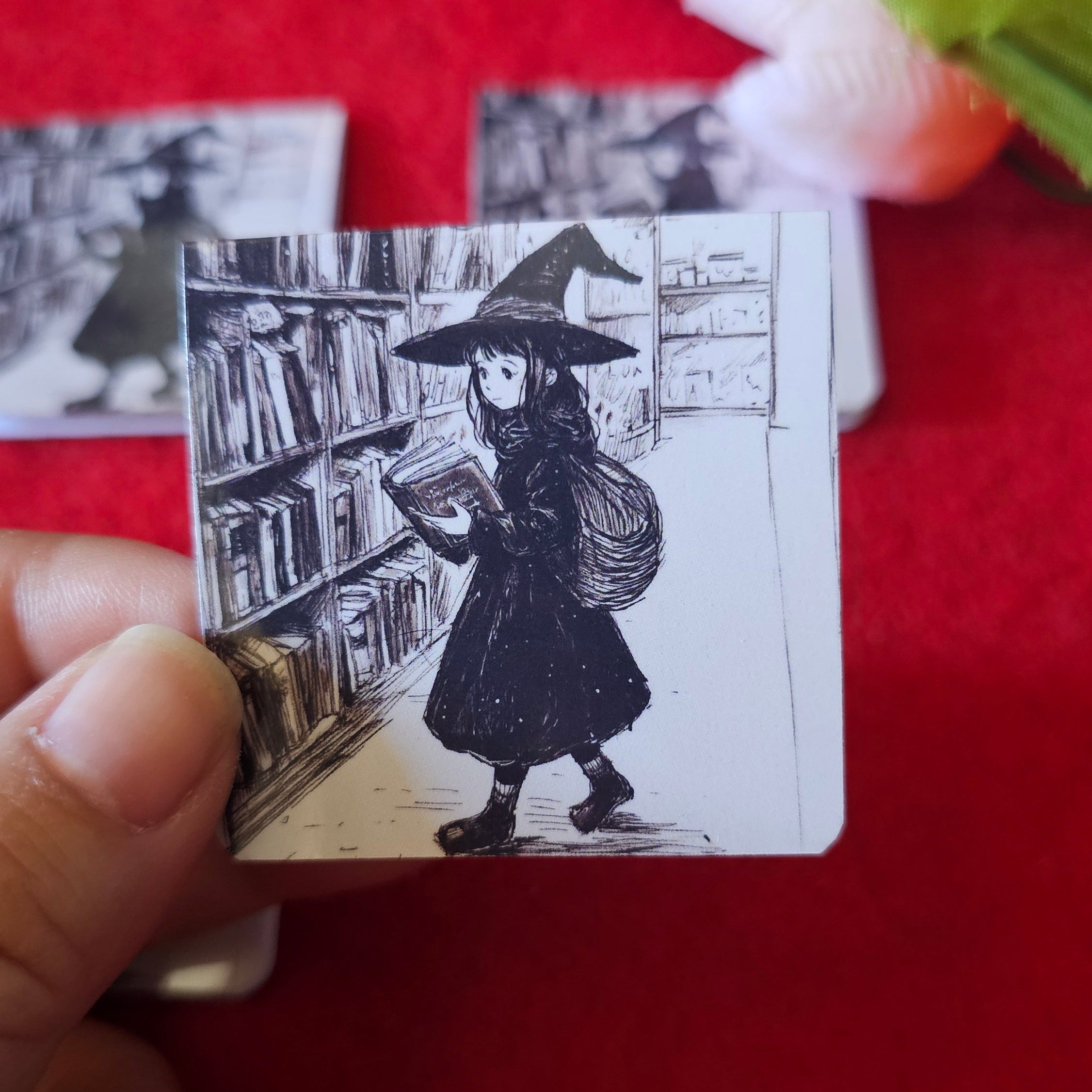 Black and watch sketch of a young witch holding a book in a bookstore.